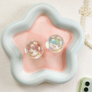 Detail of round resin phone grips with glitter stars and rabbit motif in a star dish