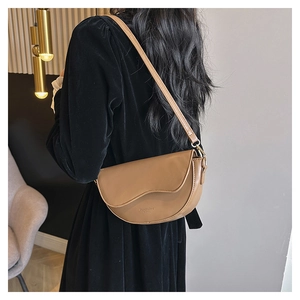 Détail du sac selle demi-lune camel montrant le rabat asymétrique et le cuir mat