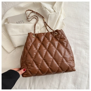 Close-up of brown quilted leather tote bag with woven metal chain shoulder straps