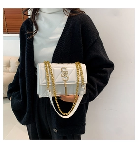 Detailed close-up of a white quilted shoulder bag featuring a gold chain strap and logo
