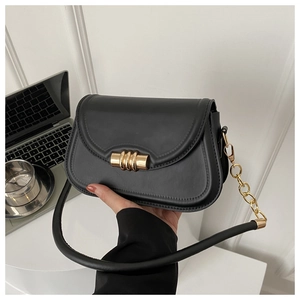 Detail of matte black leather bag featuring a gold cylindrical magnetic buckle and chain strap