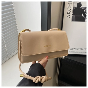 Detail der beigen Kunstledertasche mit Goldlogo und geknoteten Riemenakzenten