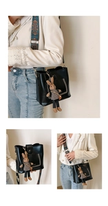 Detail view of black leather bucket bag with bohemian strap and plush rabbit charm