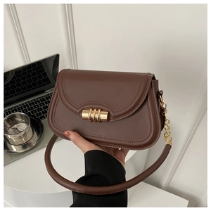 Detailed close-up of brown leather saddle bag with distinctive gold cylinder clasp buckle