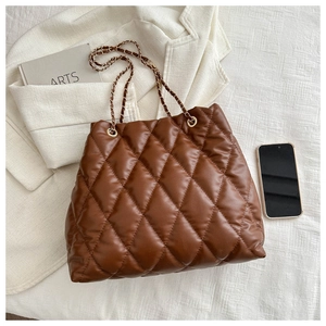 Close-up of brown quilted bucket bag with chain strap styled with aesthetic accessories