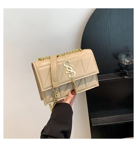 Detail of beige quilted square bag featuring gold S buckle and metal fringe tassel