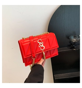 Close-up of red quilted shoulder bag with gold chain strap and tassel detail