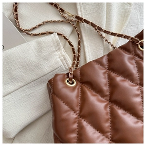 Close-up of quilted leather texture and gold chain strap on a brown bucket bag