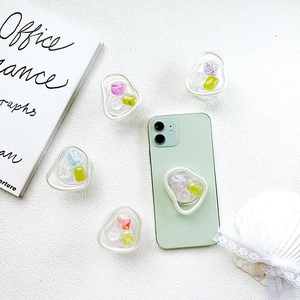 Détail de supports de téléphone transparents avec fleurs en résine et coquillages