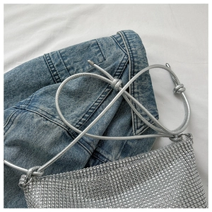 Detailansicht der silbernen Strass-Handtasche mit verknotetem Träger auf Denim