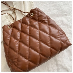 Detail of a brown quilted bucket bag featuring a gold chain strap and diamond pattern