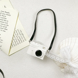 Detailed view of camera-shaped phone stand on elegant white marble with lace and shells