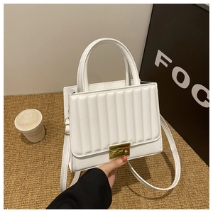 Detail of white textured handbag with vertical embossing and gold square twist lock