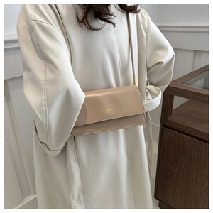 Detailansicht der beigen Crossbody-Tasche mit goldenem MISSMINI-Logo auf der Klappe