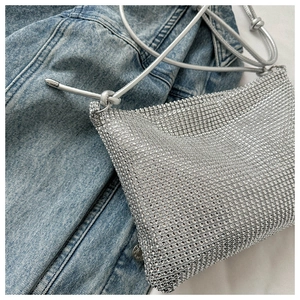 Detailansicht der silbernen Strass-Umhängetasche auf einem blauen Jeansjacken-Hintergrund