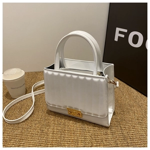 Détail du sac à main en cuir blanc avec rayures texturées et fermoir en métal doré