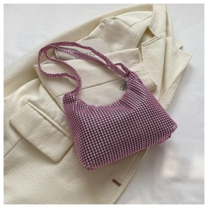 Detail of pink rhinestone shoulder bag with silver zipper on a beige suit background