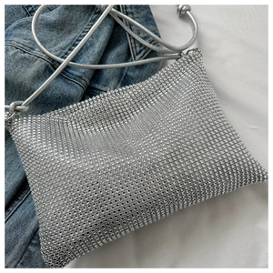 Detailaufnahme der silbernen Strass-Umhängetasche mit feinem Kordelriemen auf Denim