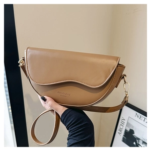 Détail d'un sac demi-lune marron avec couture ondulée et fermoir en métal doré brillant