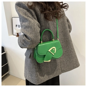 Detail of bright green saddle bag with gold D-buckle on a grey herringbone coat