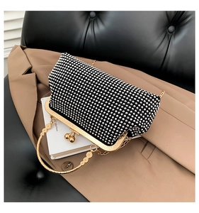 Close-up of diamond-studded black evening handbag with gold floral handle and metal frame