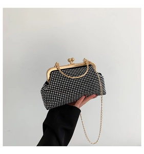 Close-up of black evening clutch with sparkling rhinestones and gold chain strap