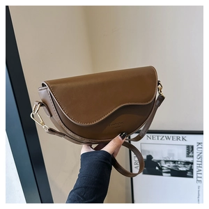 Détails du sac selle en cuir marron avec rabat ondulé et boucle en métal doré brillant