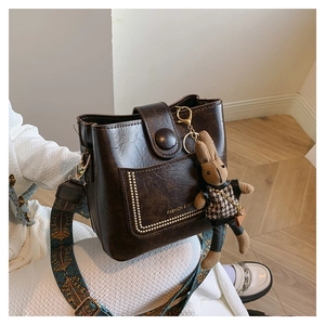 Detail of dark brown vintage bucket bag with metal rivets and floral wide strap