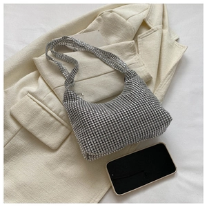 Detailed view of silver rhinestone hobo bag on a chic cream blazer with sparkling texture