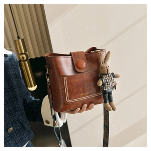 Detail of brown vintage bucket bag with stud pockets and geometric woven shoulder strap