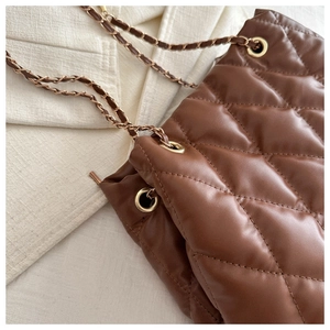 Close-up of brown quilted bucket bag with gold chain strap and luxury diamond texture