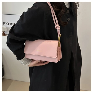 Detail der rosa Kunstledertasche mit MISS MINI Logo und geknotetem Riemen am schwarzen Mantel