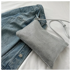 Detailaufnahme einer silbernen Strass-Abendtasche auf Denim und weißem Stoff