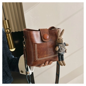 Macro detail of vintage brown leather bucket bag with stud trim and rabbit charm