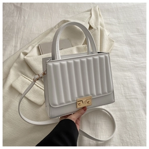 Détails du sac carré structuré blanc avec texture matelassée verticale et fermoir doré