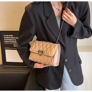Dettaglio della borsa trapuntata beige con tracolla a catena in metallo nero su modella