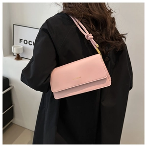 Detailansicht der rosa Ledertasche mit goldenem Logo und geknotetem Schultergurt