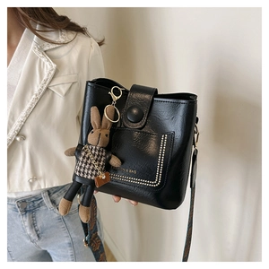 Minimalist black leather bucket bag with gold rivets and vintage printed strap on model