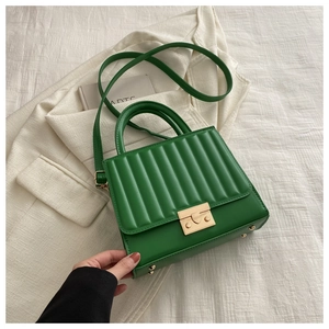 Détail du sac en cuir matelassé vert vif avec fermoir carré doré et poignée supérieure