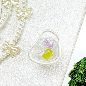Détail du support de téléphone floral avec nacre et pierres vertes sur fond texturé