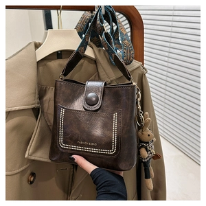 Detail of dark brown leather bucket bag featuring polka dot embroidery and a bunny charm