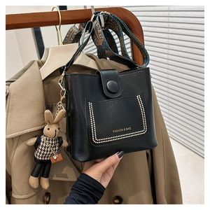 Detail of black leather bucket bag with gold beaded pocket and floral wide strap