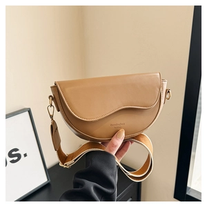 Détail du sac selle camel en similicuir avec large bandoulière en tissu tressé