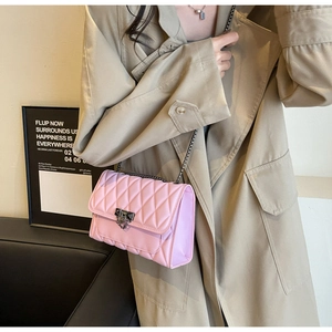 Dettaglio borsa trapuntata rosa con chiusura in metallo indossata su un trench beige