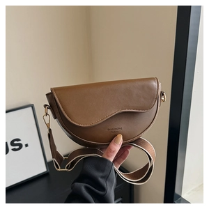 Gros plan sur une sacoche en cuir marron avec sangle jacquard et crochets dorés