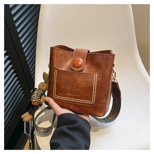 Close-up of vintage brown bucket bag with ethnic wide strap and rabbit charm detail