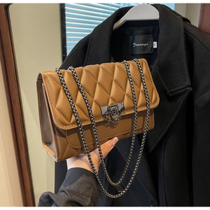 Dettaglio di una borsa a catena trapuntata marrone con chiusura in metallo su un cappotto