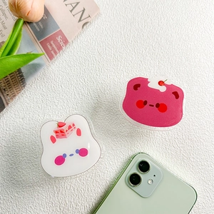Detail of cute acrylic phone grips with bear and rabbit motifs on a green smartphone