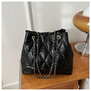 Close-up of quilted black tote bag featuring chain straps and elegant metal eyelet details