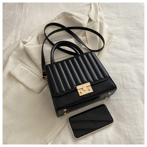 Détail du sac à main noir avec rabat plissé vertical et fermoir en métal doré élégant